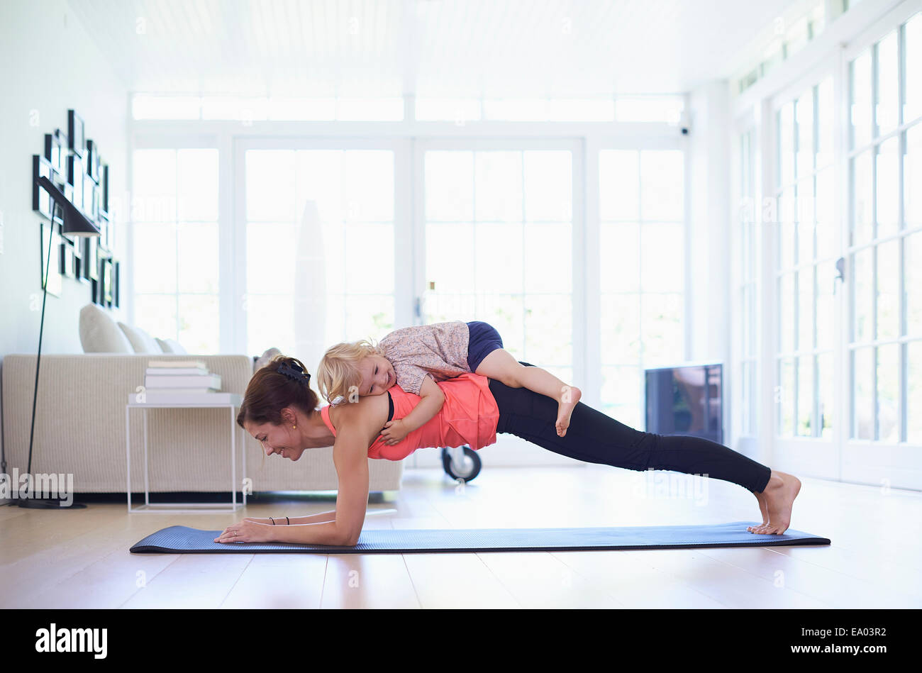 Metà adulto madre la pratica dello yoga con toddler figlia sulla parte superiore della sua Foto Stock