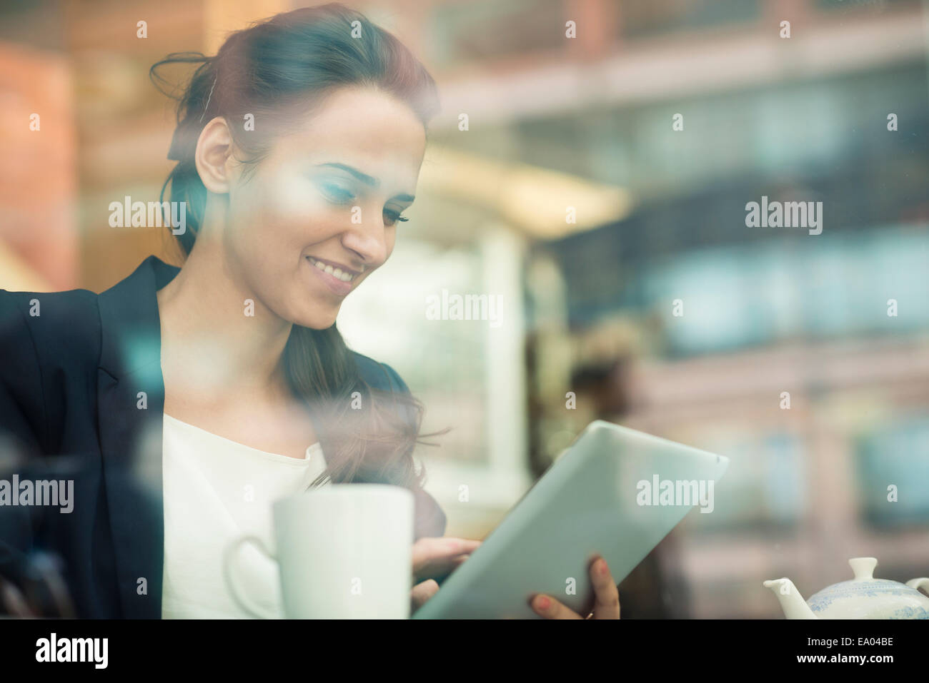 Imprenditrice mediante schermo tattile sulla tavoletta digitale in cafe, London, Regno Unito Foto Stock