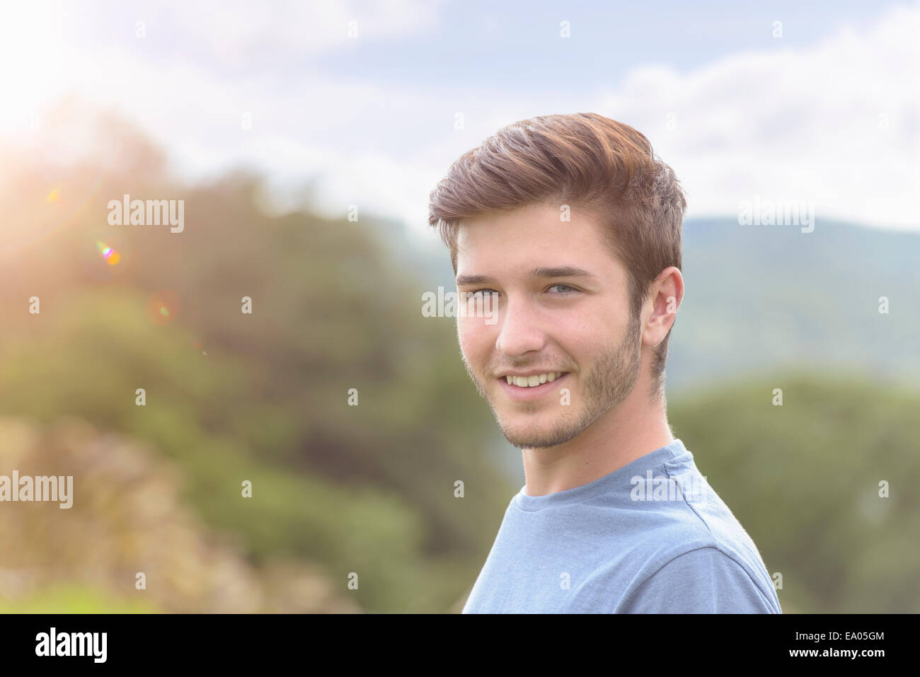 Ritratto di giovane uomo sorridente sotto la luce diretta del sole Foto Stock
