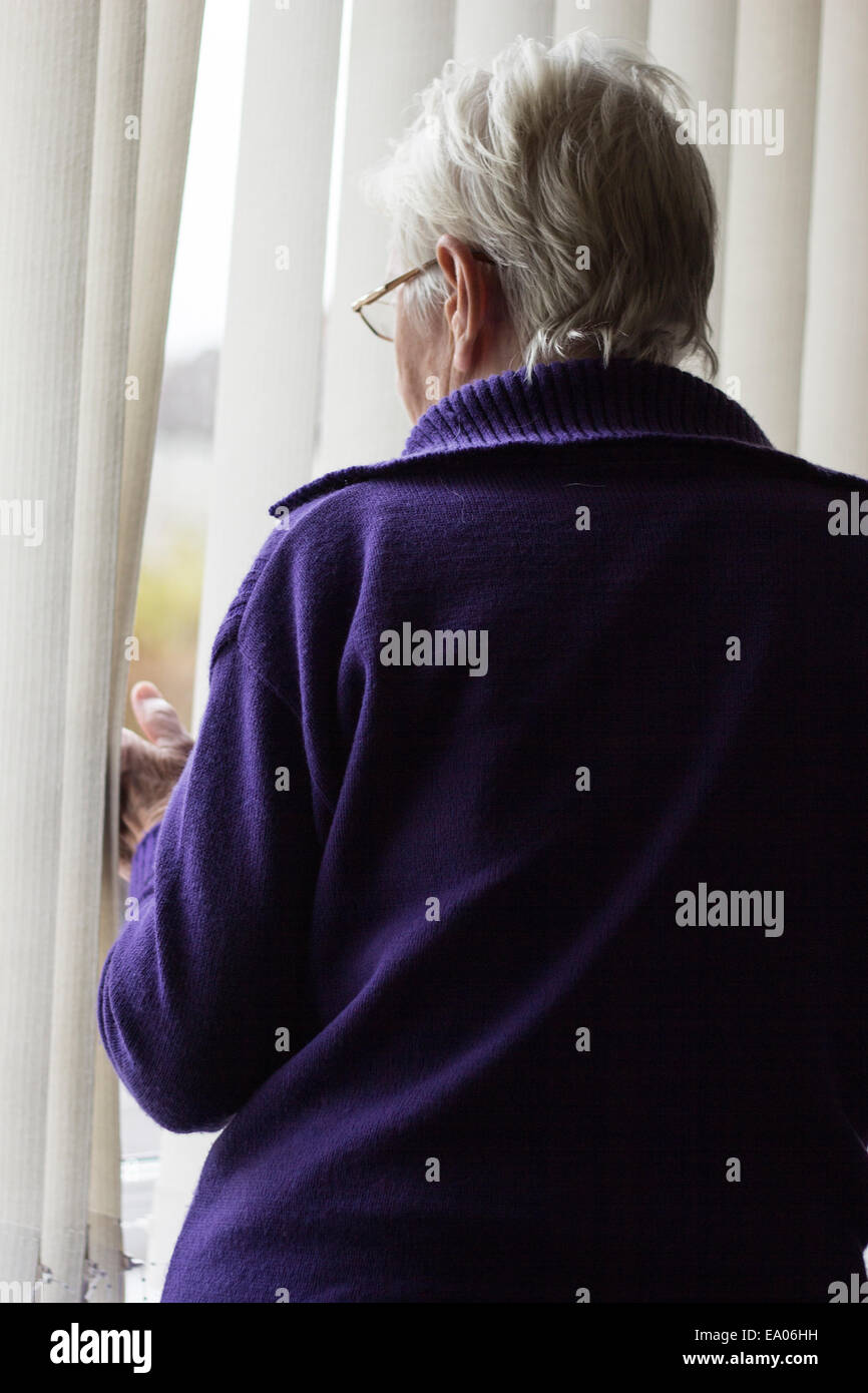 Signora anziana lookin fuori dalla finestra Foto Stock