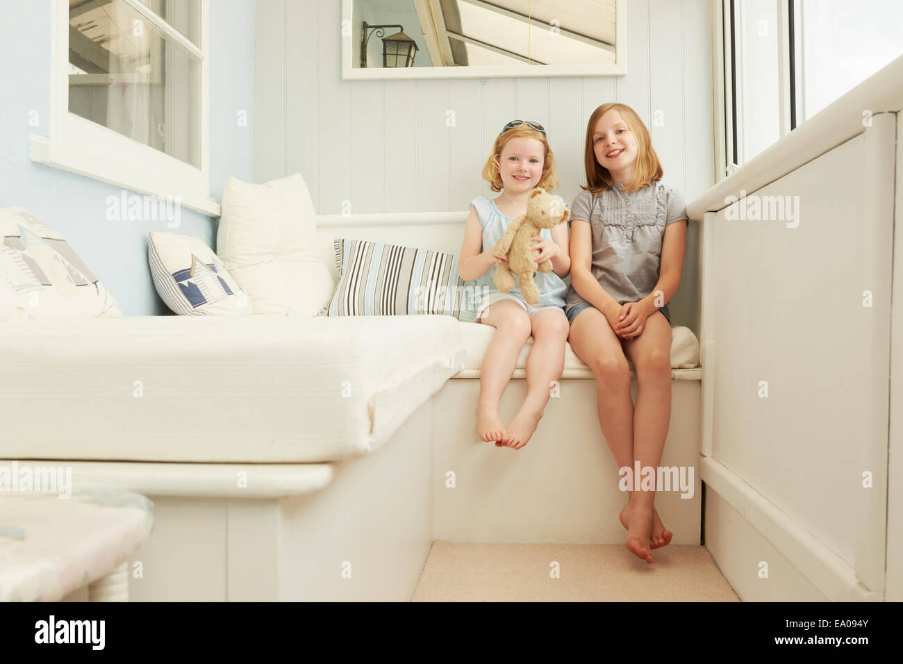 Ritratto di due sorelle seduta in appartamento di vacanza portico Foto Stock