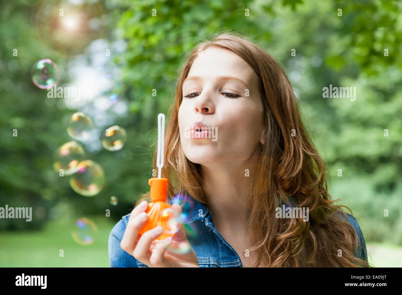 Giovane donna a soffiare bolle in giardino Foto Stock