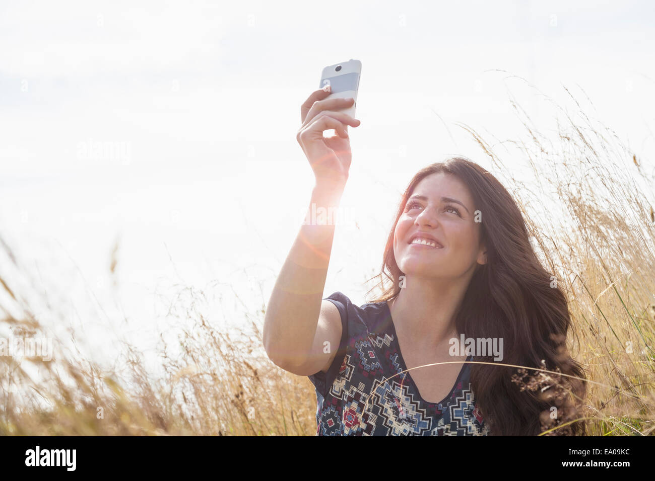 Giovane donna prendendo selfie con lo smartphone nel campo Foto Stock