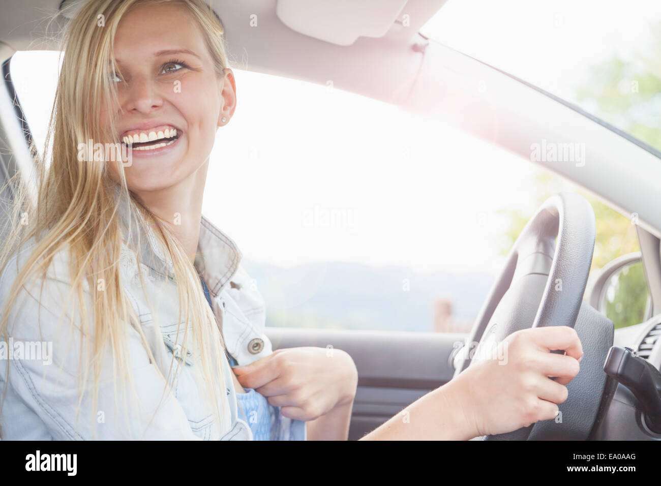 Giovane donna sorridente dietro al volante della vettura Foto Stock