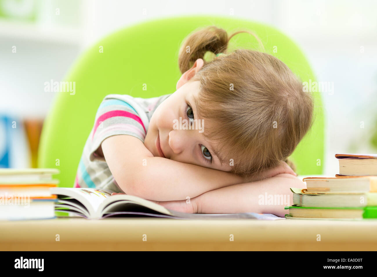 Bambino felice ragazza con pila libri a tavola Foto Stock