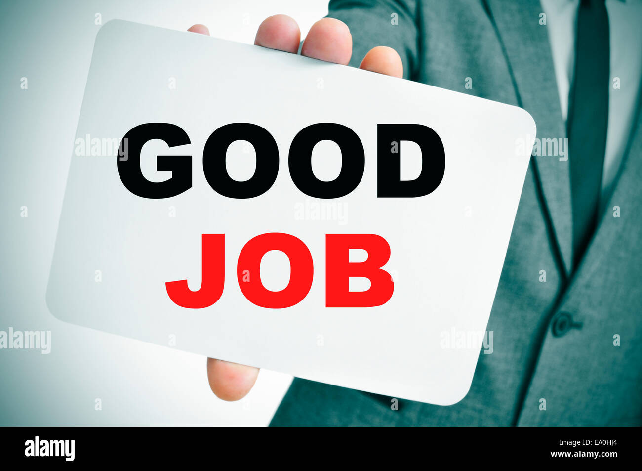 Un giovane imprenditore in un abito grigio tenendo un cartello con scritto il testo buon lavoro scritto in esso Foto Stock