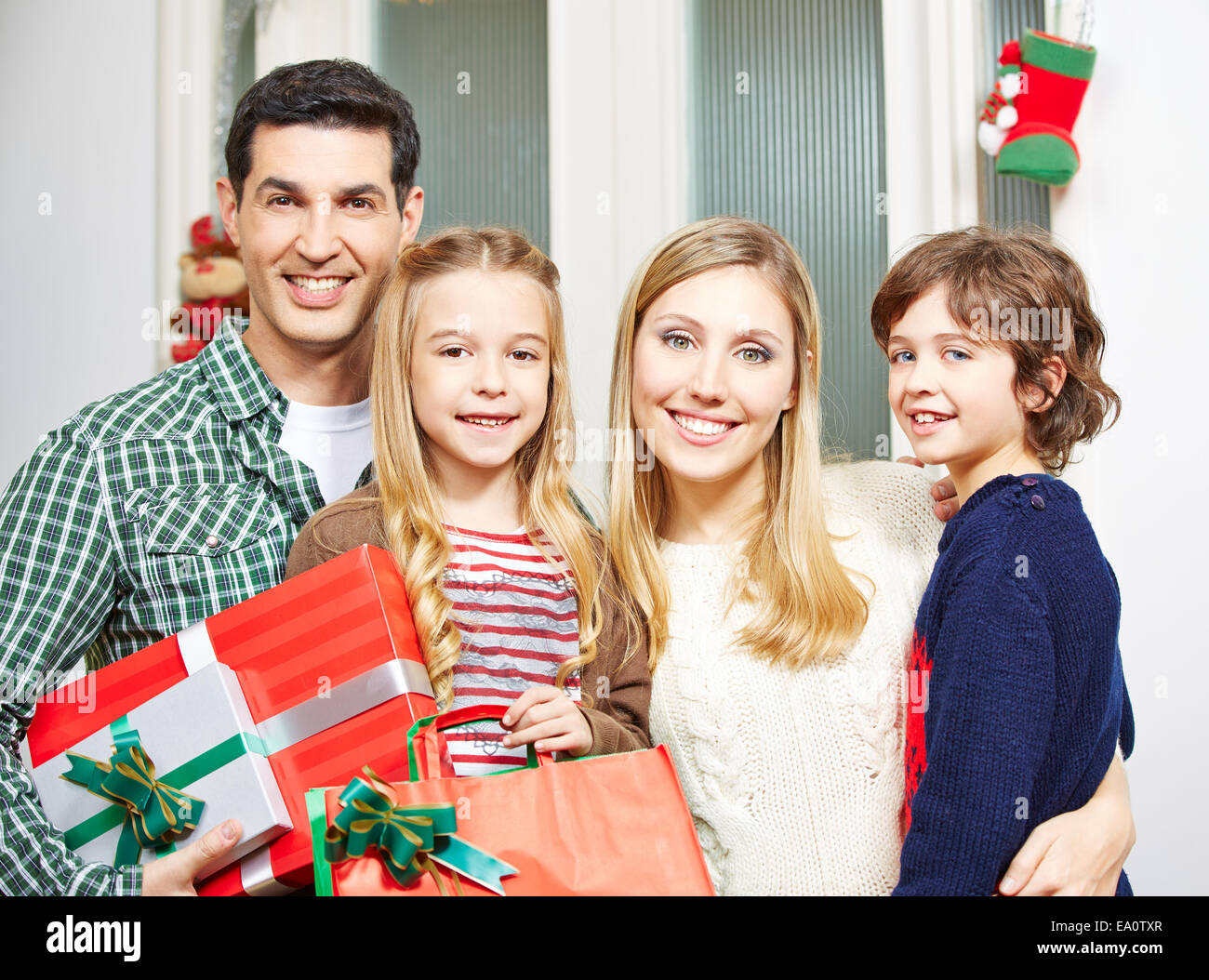 Felice famiglia con due bambini con doni alla vigilia di Natale Foto Stock
