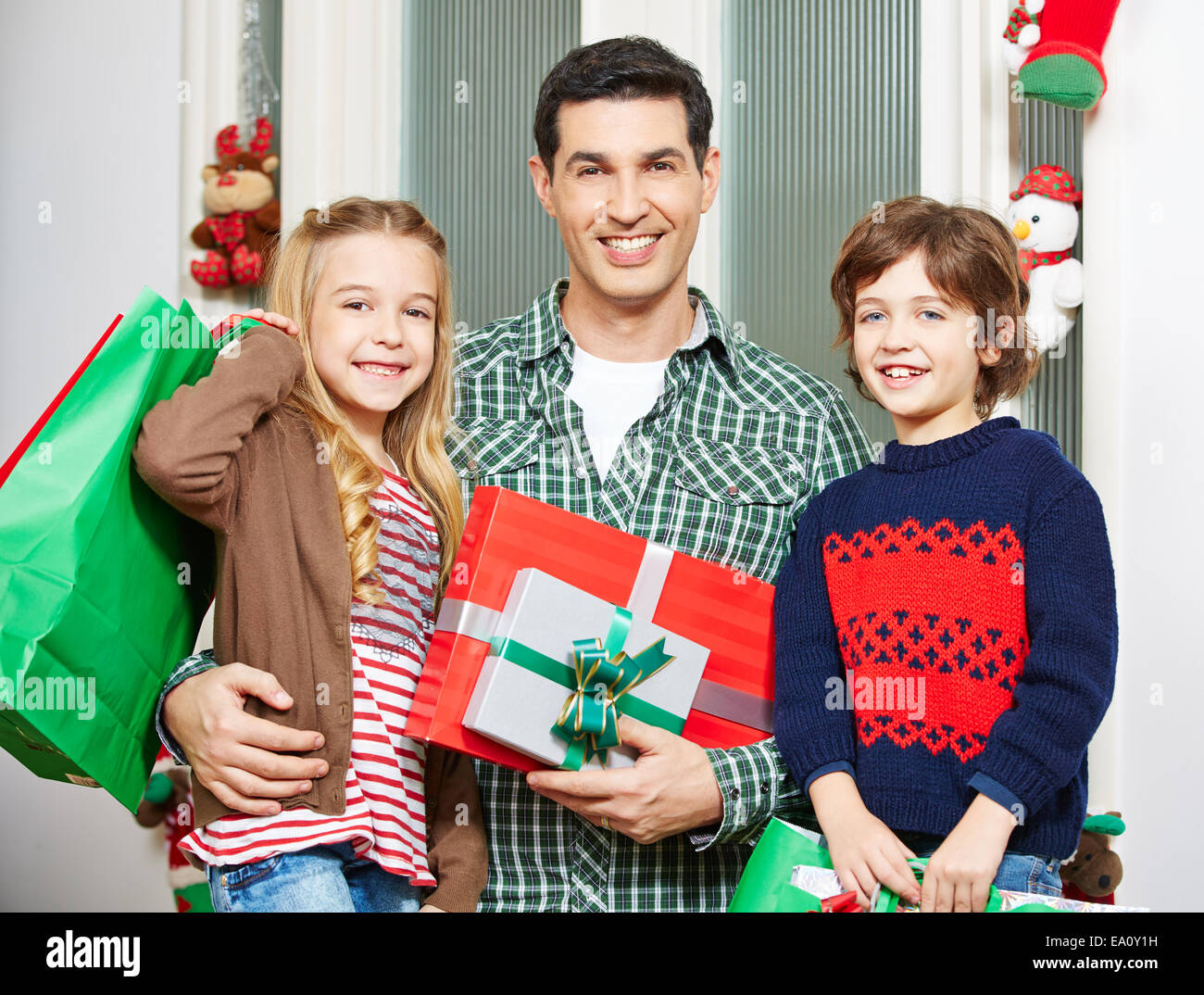 Padre Felice con due bambini e doni alla vigilia di Natale Foto Stock