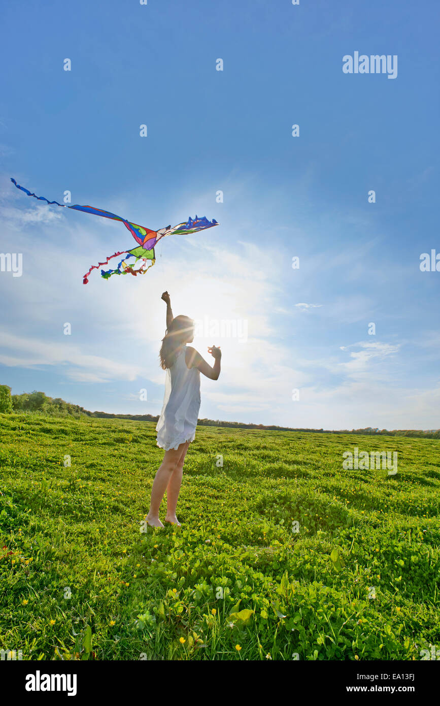 Giovane donna volare un aquilone nel campo Foto Stock