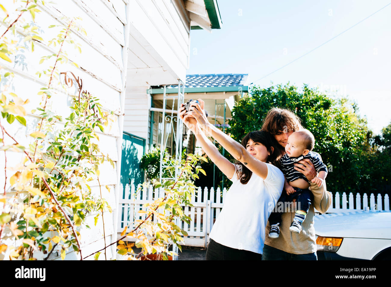 Donna tenendo famiglia selfie in corrispondenza della parte anteriore della casa Foto Stock