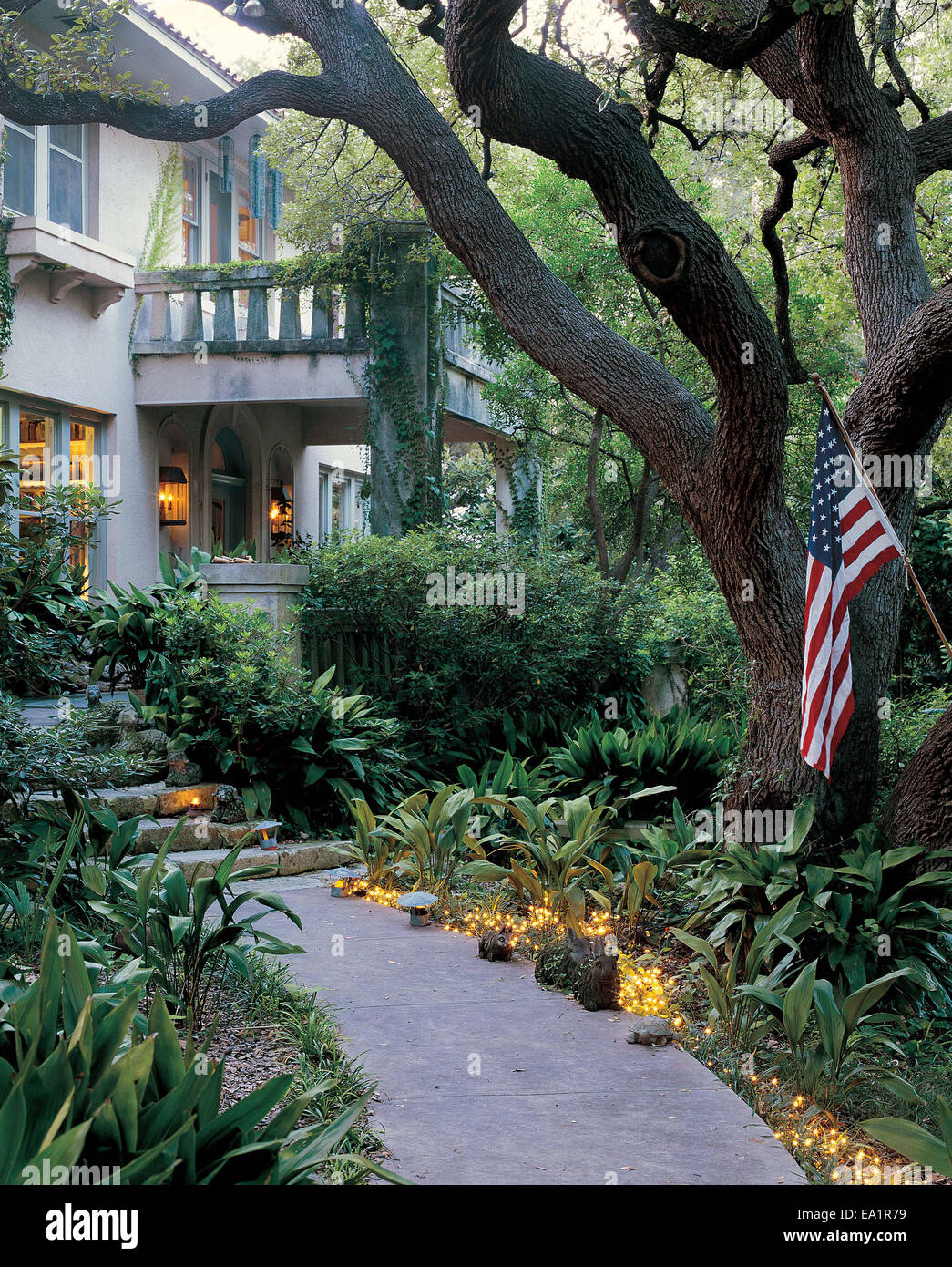 Giardino illuminato percorso con bandiera americana porta a porta anteriore della casa di pietra Foto Stock