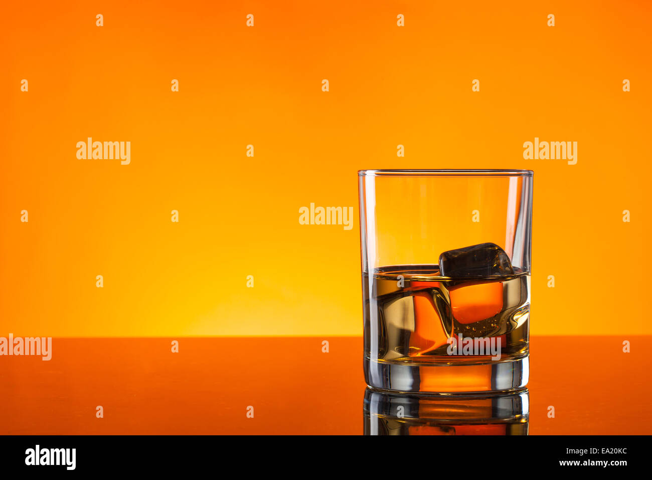 Drink di whiskey riflessa sul vetro con sfondo arancione Foto Stock