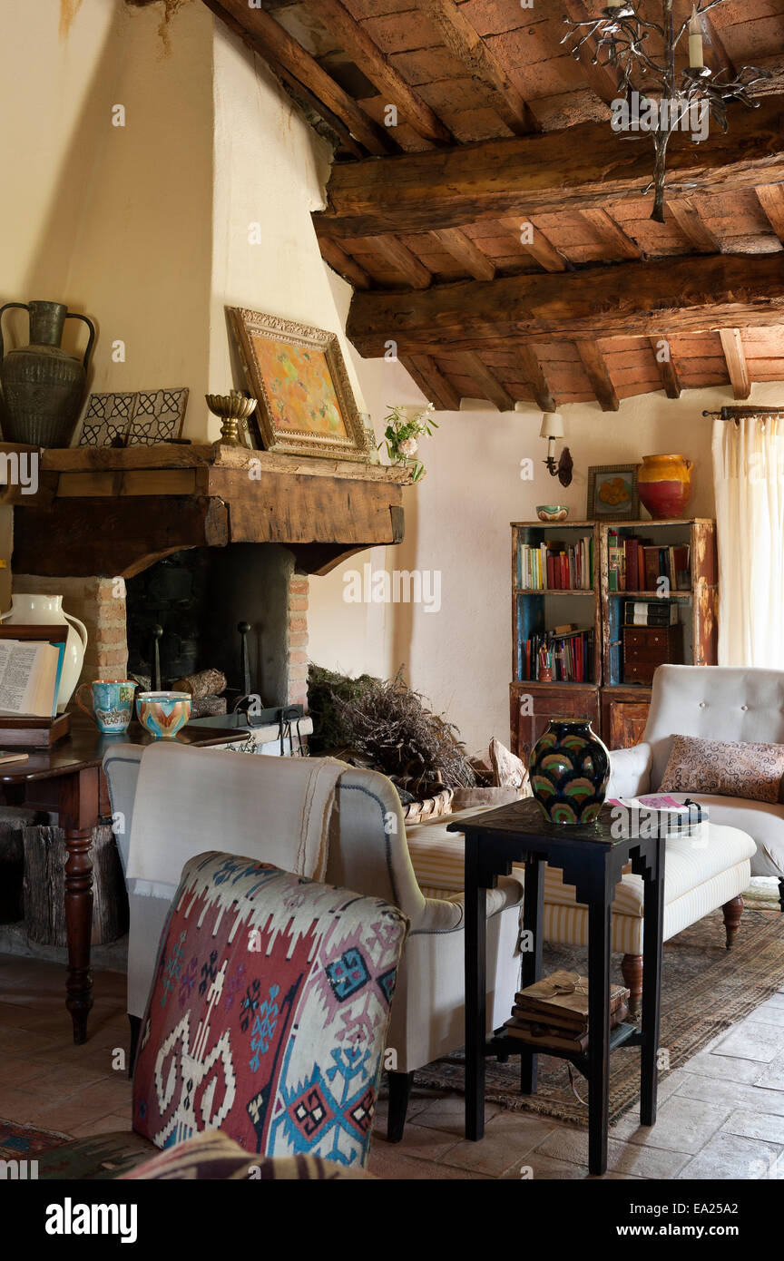 Sedia rivestita in moquette turco tessuto in soggiorno con originale soffitto a travi e grande camino in pietra Foto Stock