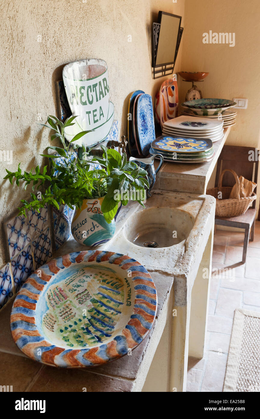Dipinto a mano le piastre sulla cucina piastrellata ledge con lavello in pietra e vintage segno dello smalto Foto Stock