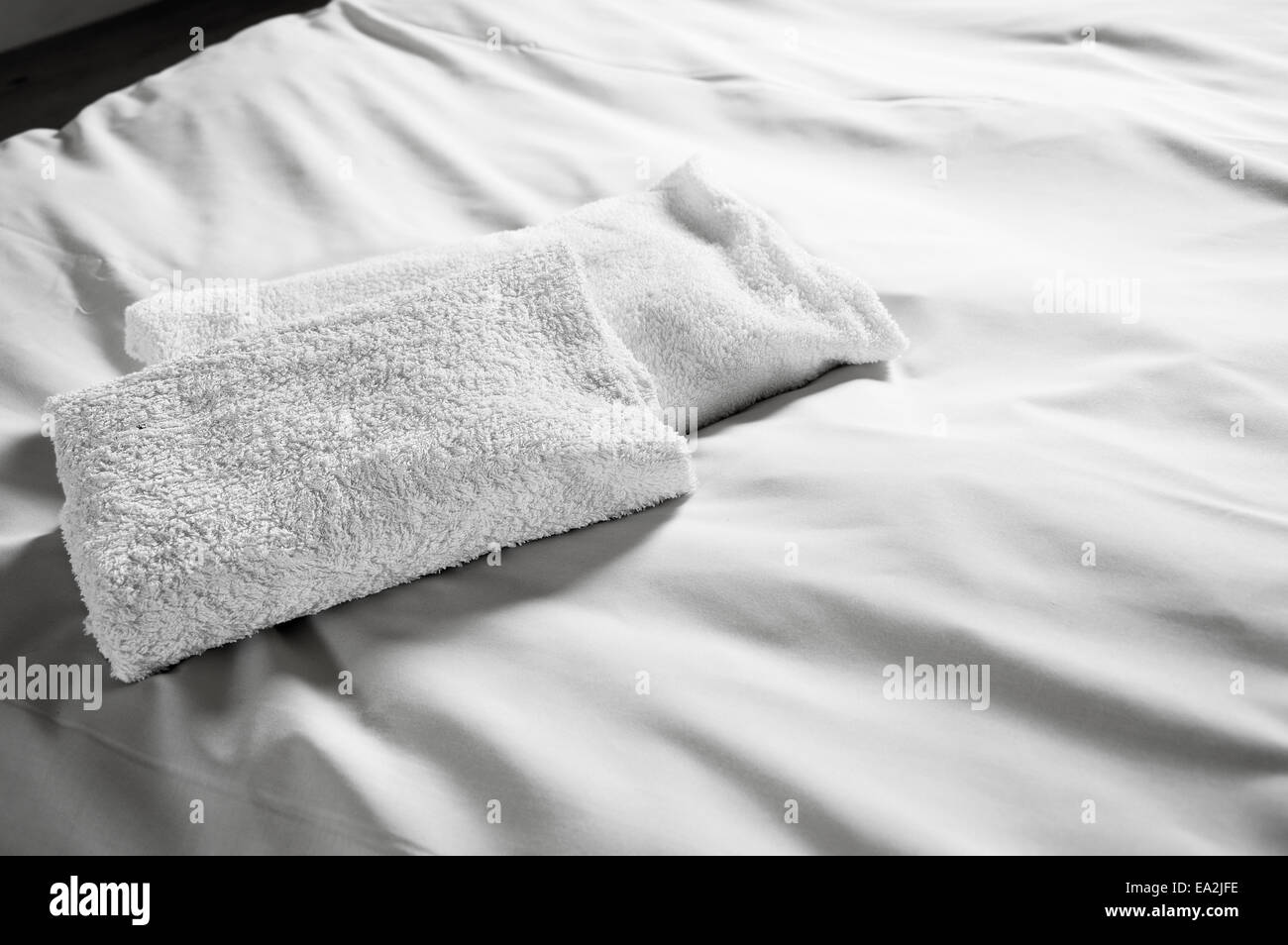 White hotel asciugamani sul letto bianco. Immagine in bianco e nero. Foto Stock