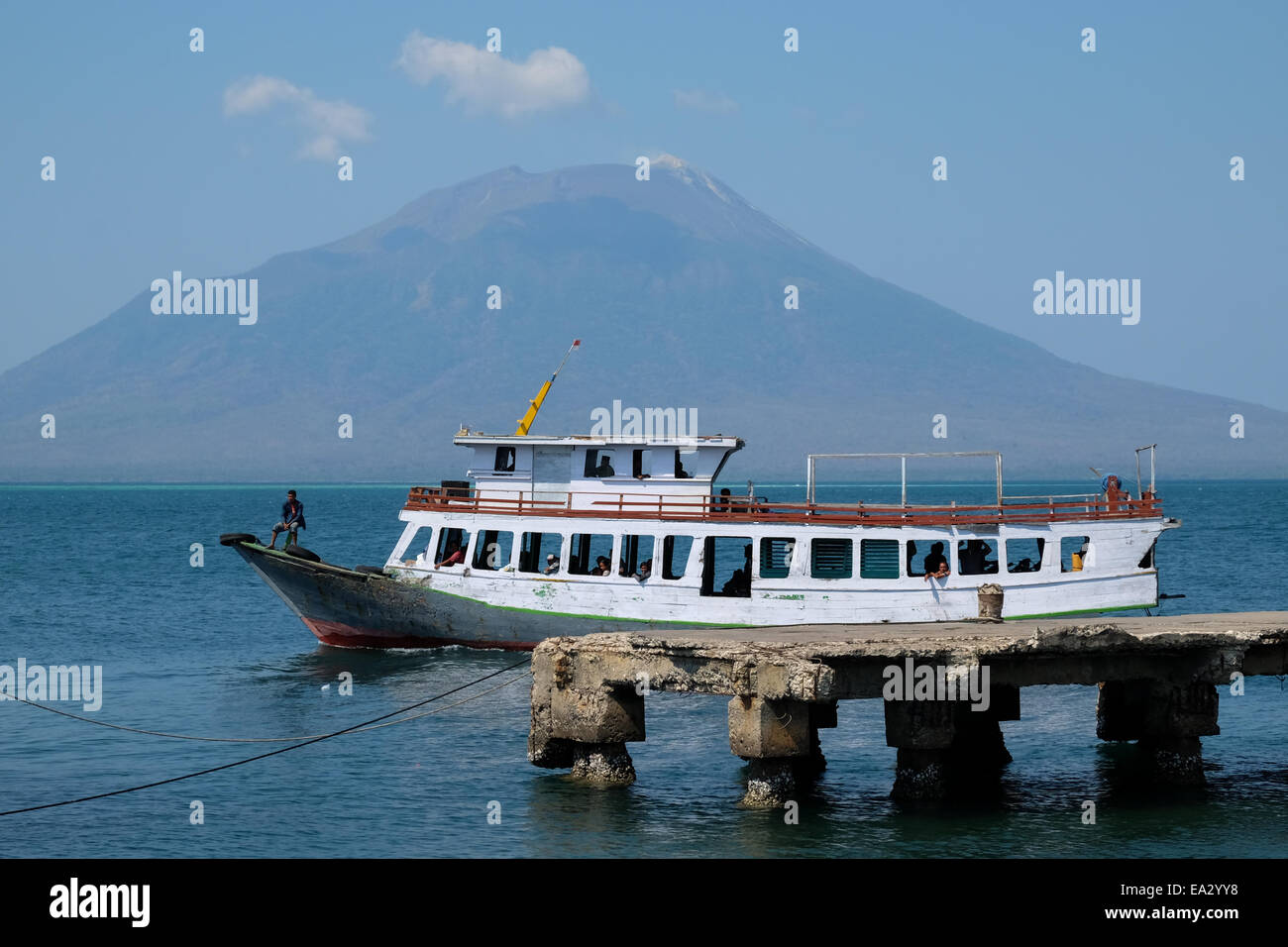 Un trasporto pubblico barca si avvicina Lewoleba porta, Lembata, Nusa Tenggara orientale, Indonesia. Mt Lewotolok a distanza. Foto Stock