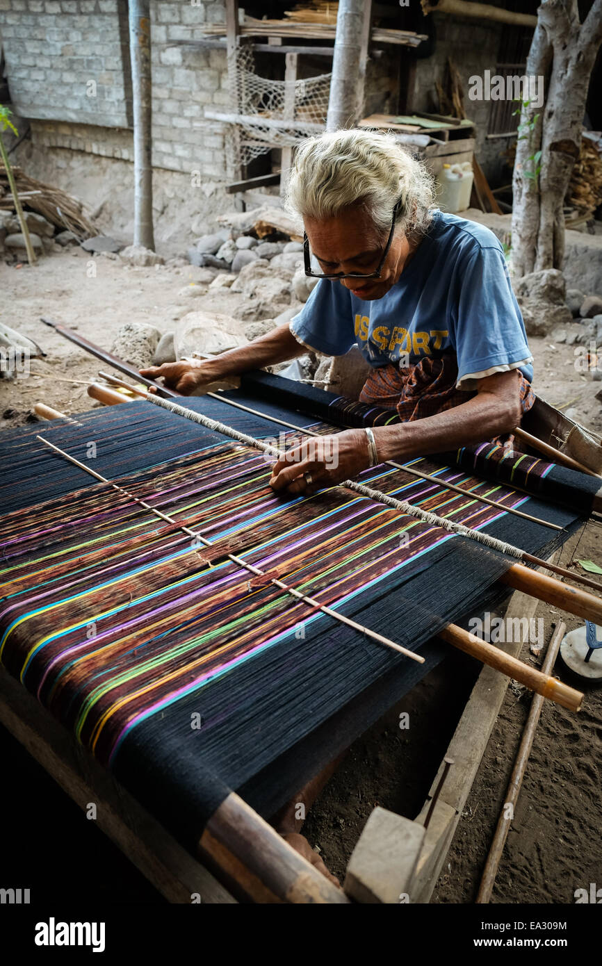 Una donna anziana tesse tessuti tradizionali chiamati ikkat presso il proprio laboratorio nel villaggio Lamagute, Lembata, Indonesia. Foto Stock