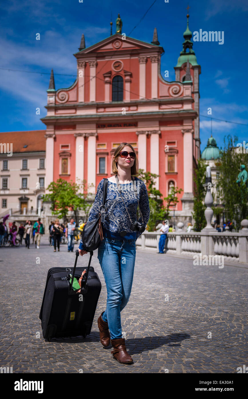 Tourist con la valigia, oltrepassando la chiesa francescana dell Annunciazione in Piazza Preseren, Lubiana, Slovenia, Europa Foto Stock