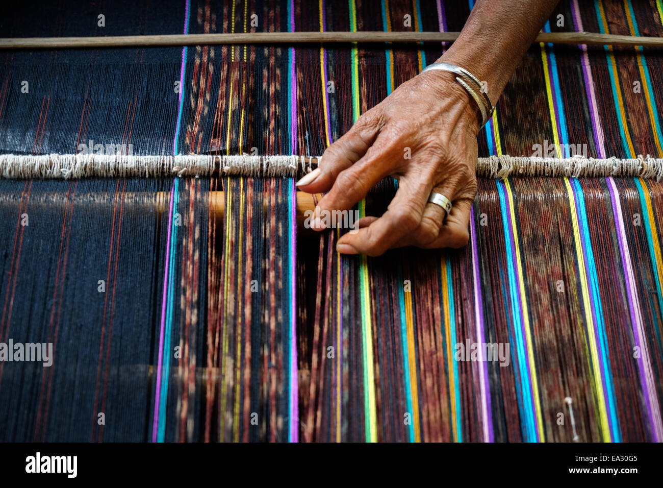 La mano di una donna vecchia tessitura di tessuti tradizionali chiamati ikat mostrando presso il proprio laboratorio nel villaggio Lamagute, Lembata, Indonesia. Foto Stock