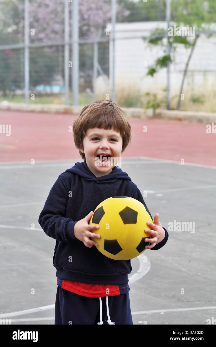 Un bambino gioca con una sfera di colore giallo Foto Stock