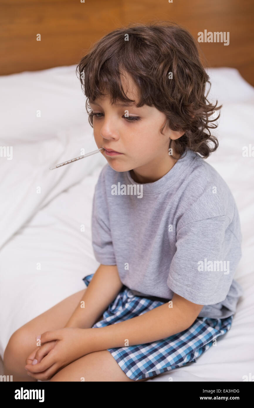 Bambino malato con termometro seduta nel letto Foto Stock