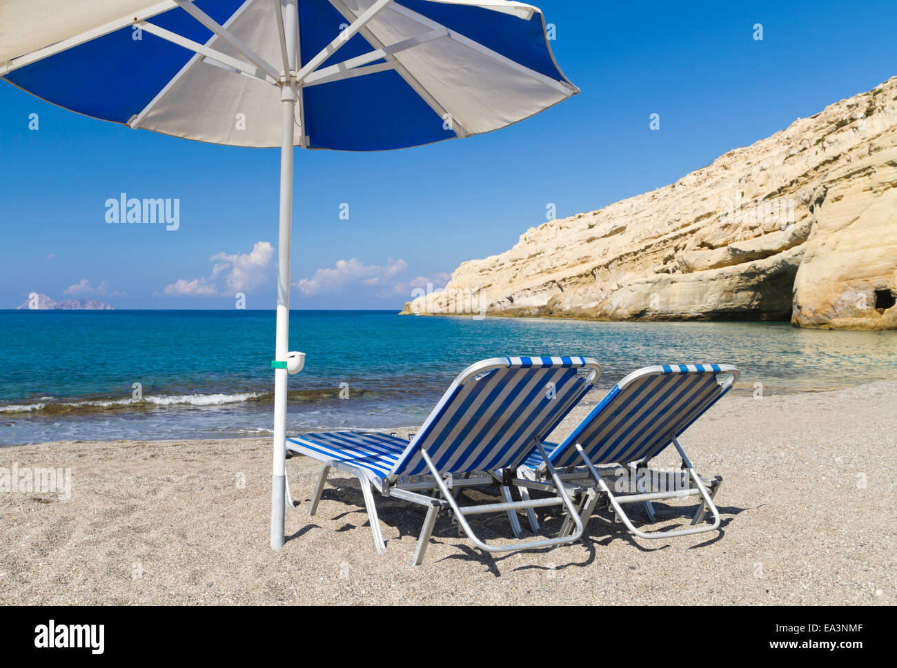 Vacanze e Turismo di concetto. Due strisce blu di sedie a sdraio e un ombrellone su una spiaggia di sabbia Foto Stock