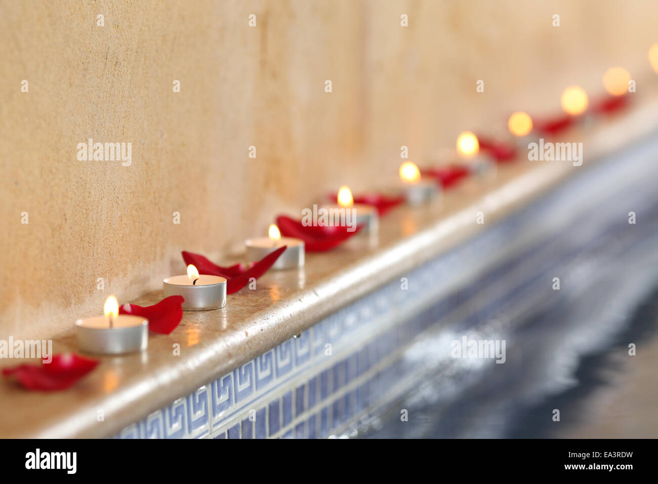Close up di candele accese e petali di rosa in una spa romantica a bordo piscina e relax concept Foto Stock
