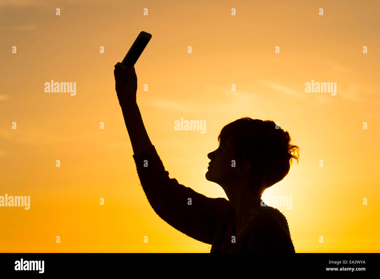 Una ragazza stagliano possiede un telefono cellulare per l'aria per cercare e ricevere un segnale di dati. Foto Stock