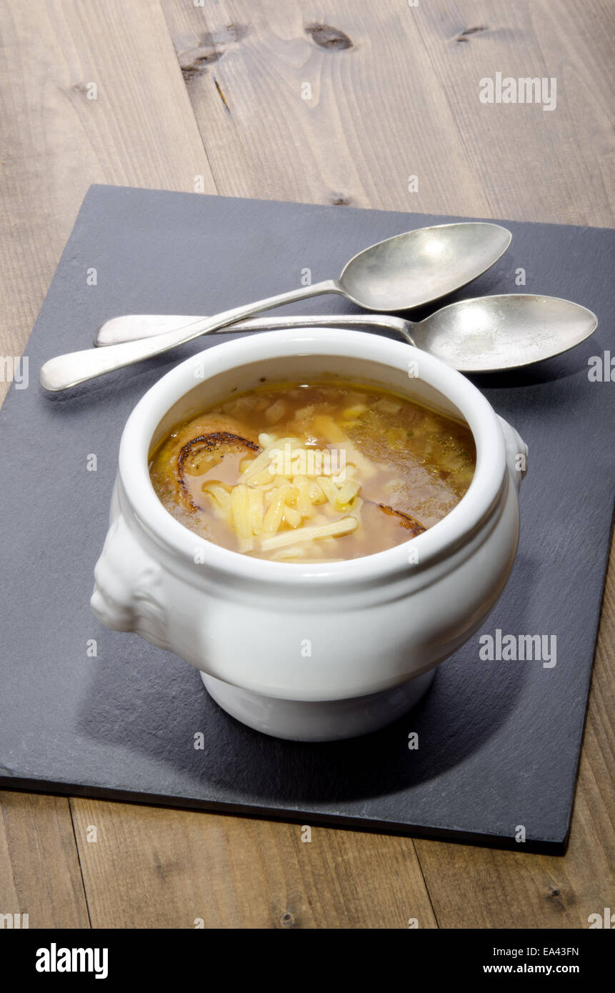 Zuppa di cipolle francese in una ciotola con cucchiaio sull'ardesia Foto Stock