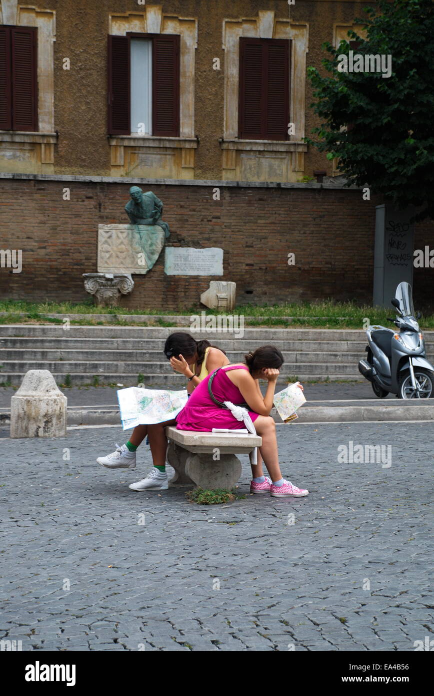 Due donne turisti seduta sul banco di lavoro nel centro di Roma lettura mappe per le direzioni e interessi. Foto Stock