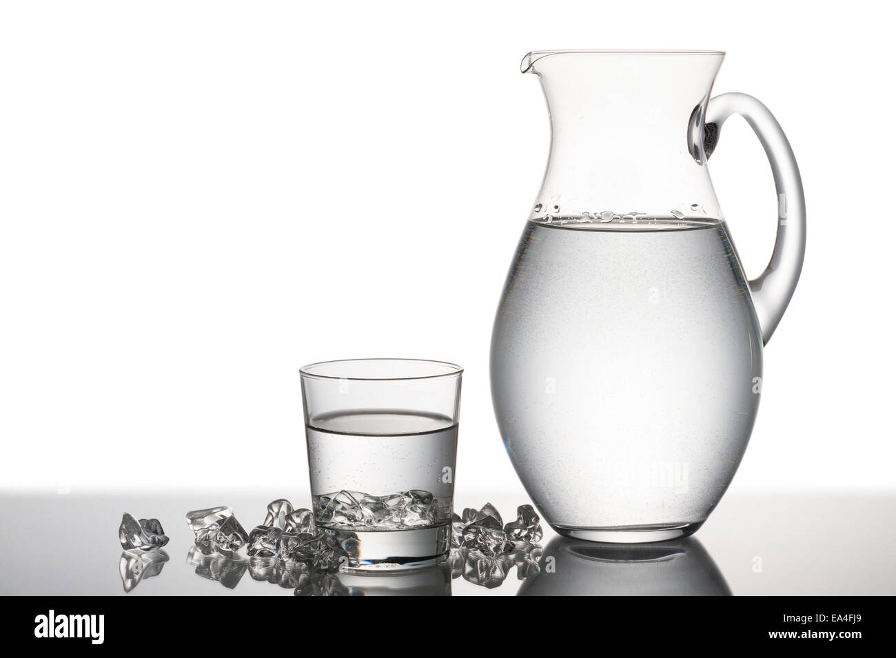 Brocca e bicchiere pieno di acqua con pezzi di cubetti di ghiaccio Foto Stock