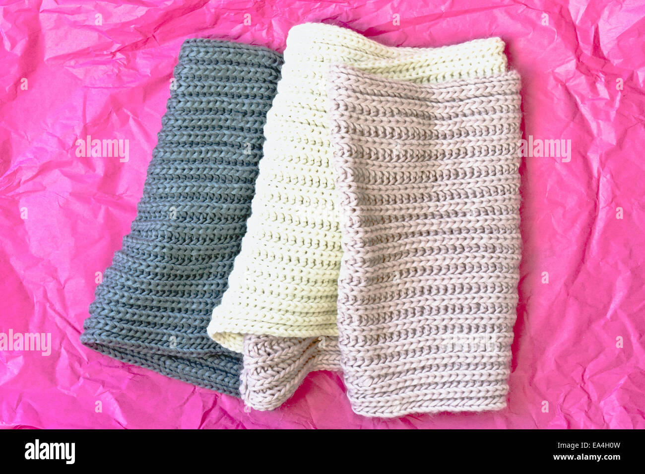 Un piegato sciarpa di lana su un pezzo di tessuto rosa carta Foto stock -  Alamy