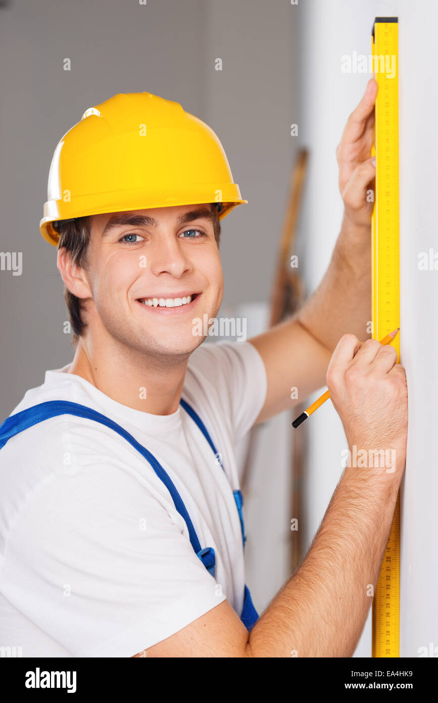 Repairman misurando con livello di builder Foto Stock