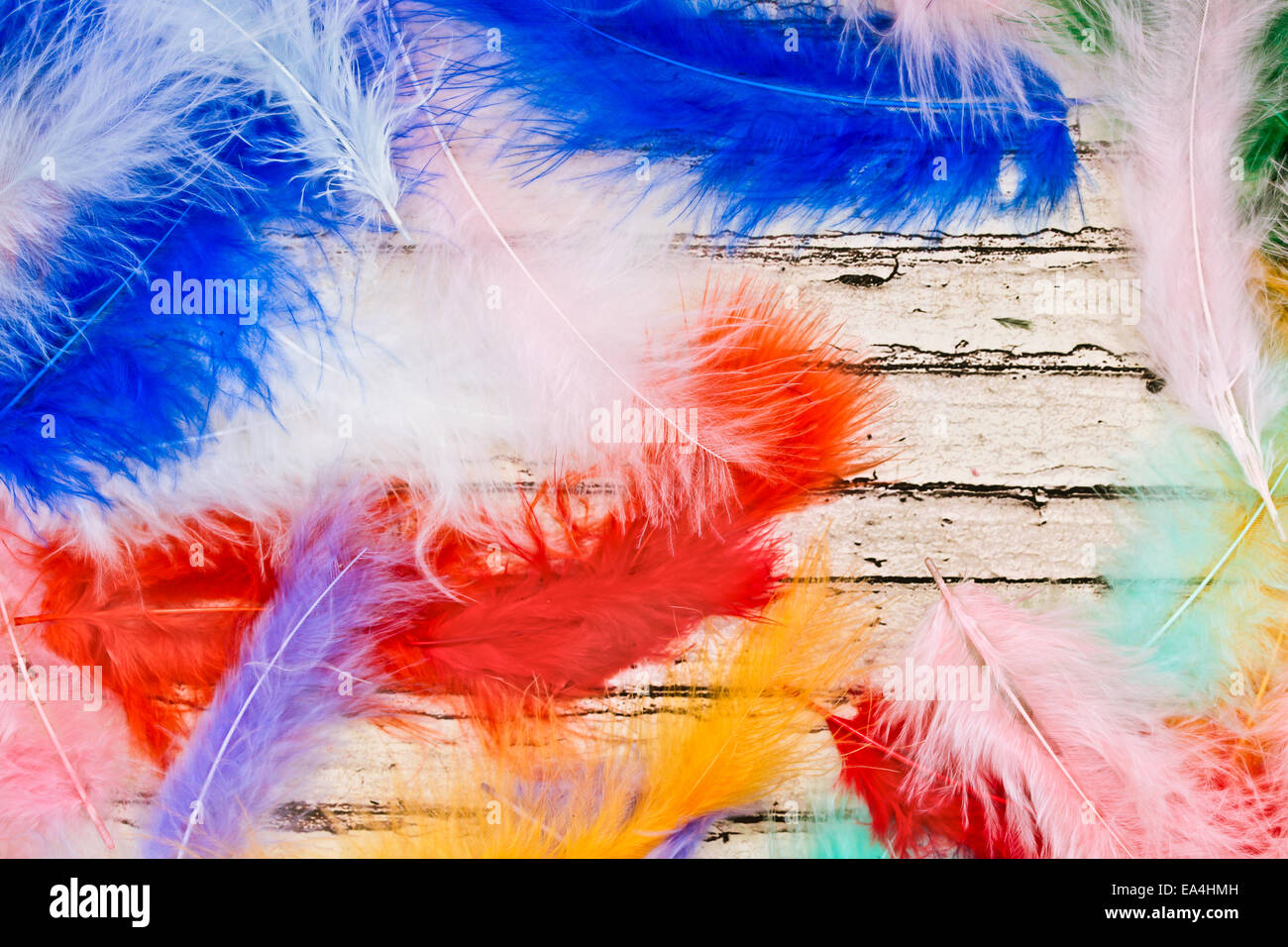 Piume colorate su di una superficie di legno come immagine di sfondo Foto Stock