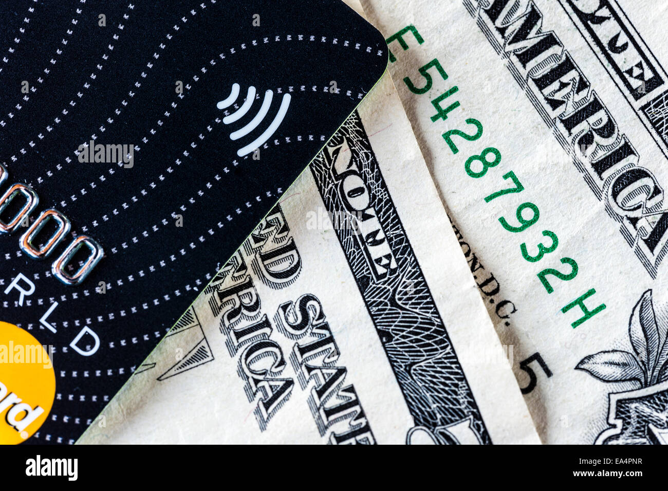 Il Near Field Communication logo su una carta di credito, contro uno sfondo di fatture del dollaro Foto Stock