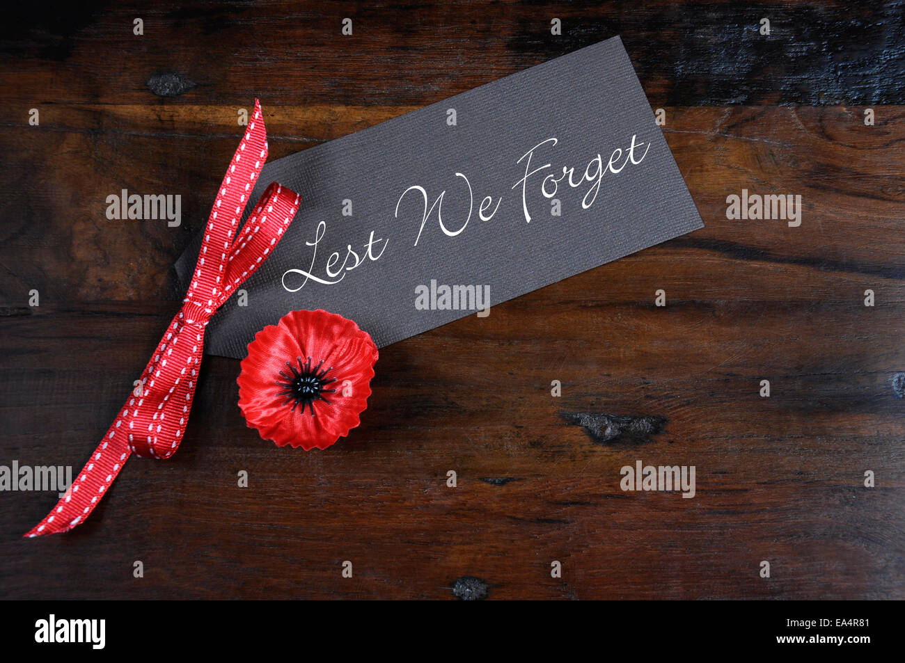 Non dimentichiamolo, Rosso papavero Fiandre Spilla distintivo per il 11 novembre, Giorno del Ricordo appello, in scuro legno riciclato sfondo. Foto Stock