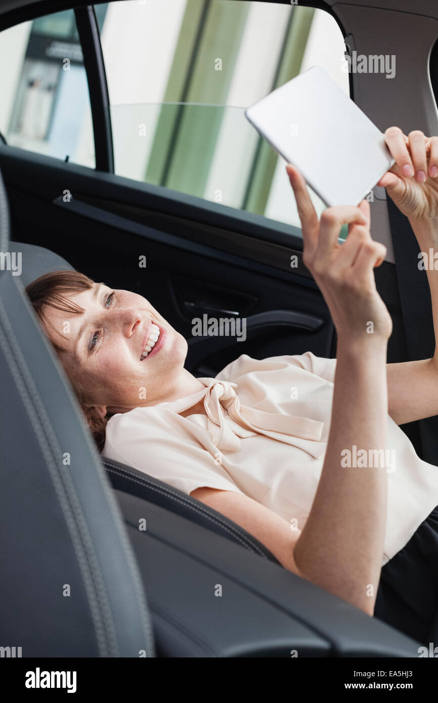 Germania, ritratto di sorridere imprenditrice prendendo in selfie nella sua auto con tavoletta digitale Foto Stock