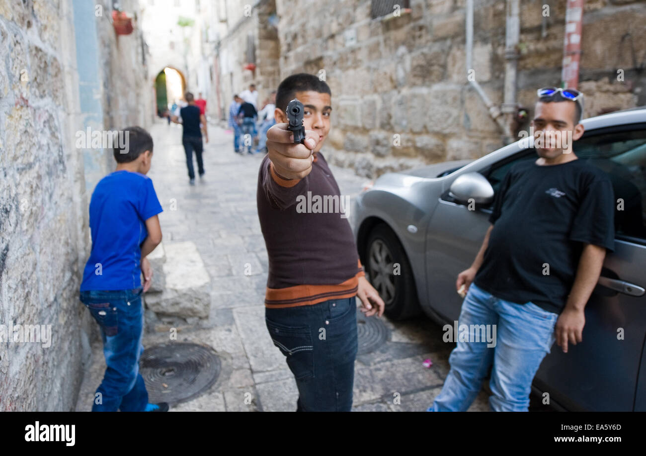 Tre giovani musulmani adolescenti sono la riproduzione di 'guerra giochi' per le strade del quartiere musulmano di Gerusalemme. Foto Stock