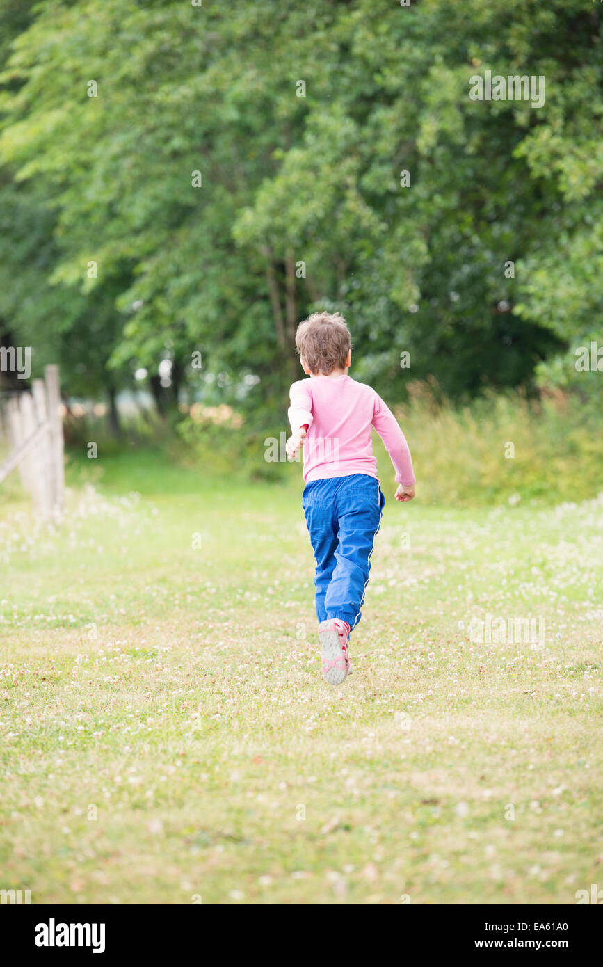 Bambina 4-5 anni in esecuzione in estate verde paesaggio, Svezia Foto Stock