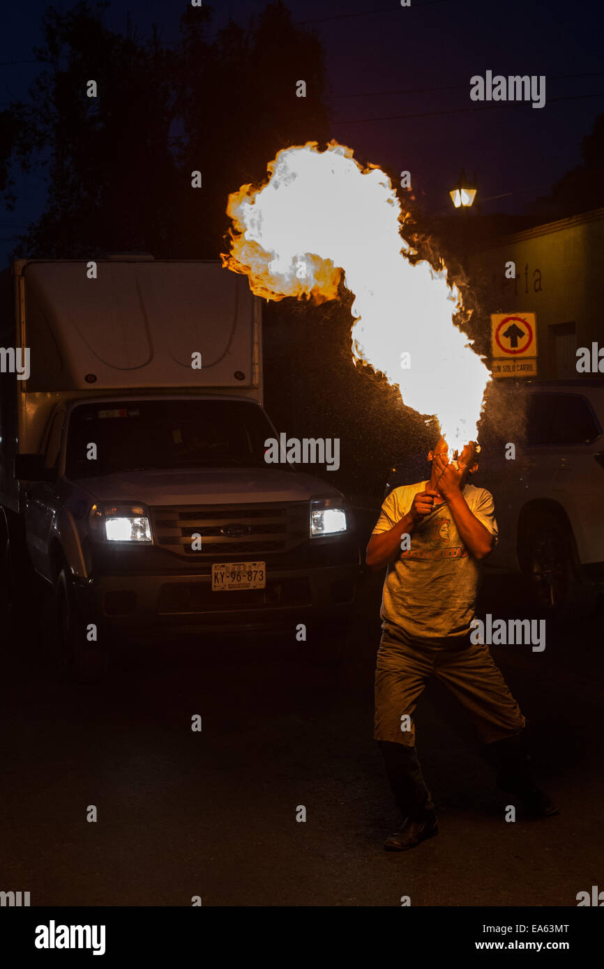 Un giovane messicano tragafuego o mangiafuoco esegue mediante soffiaggio di carburante diesel al di fuori della sua bocca in aria incendiato nel ritorno per pochi pesos da driver Novembre 62, 2014 in Oaxaca, Messico. Un singhiozzo può causare la morte immediata e la bocca del cancro è luogo comune con gli esecutori. Foto Stock