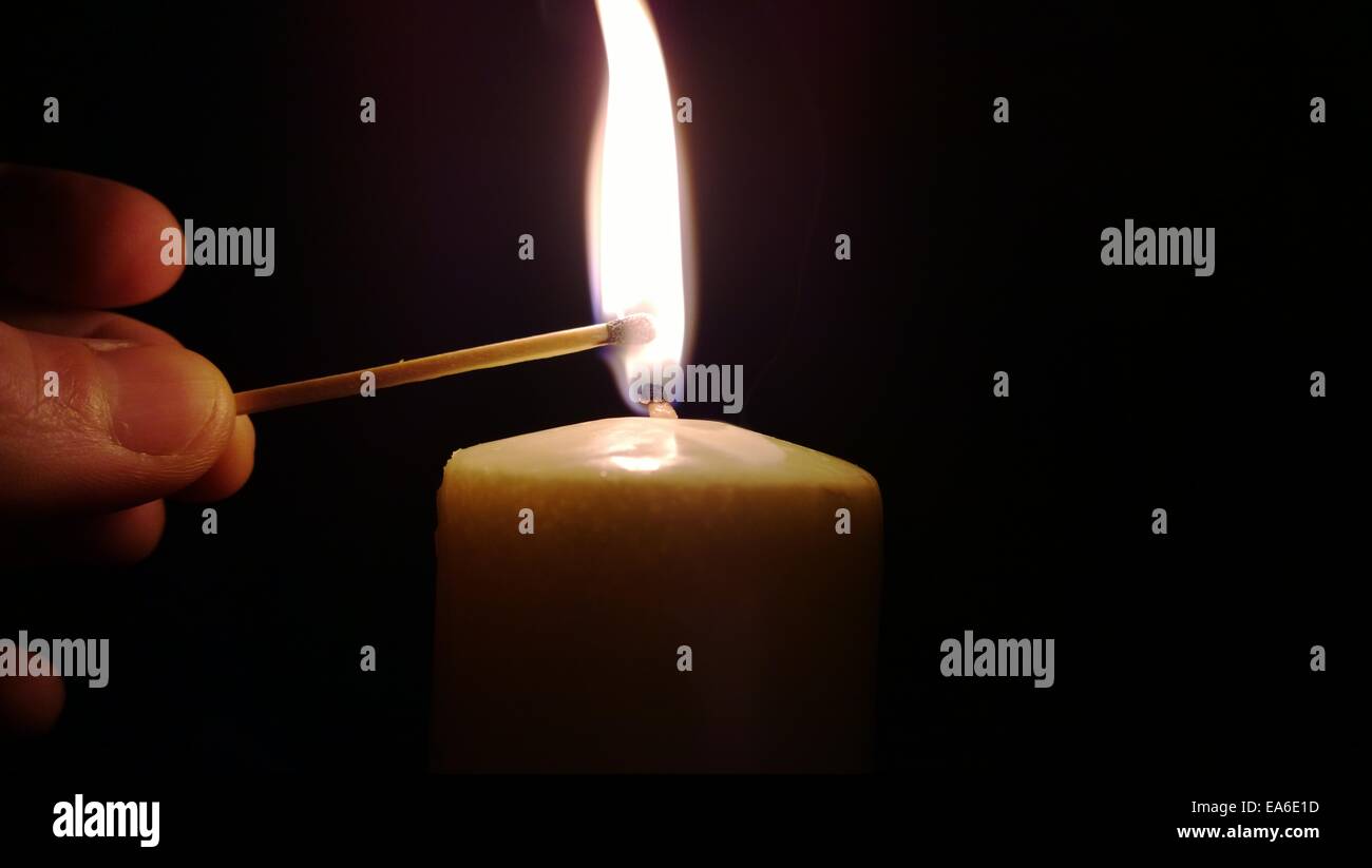 Uomo che illumina una candela con una partita Foto Stock