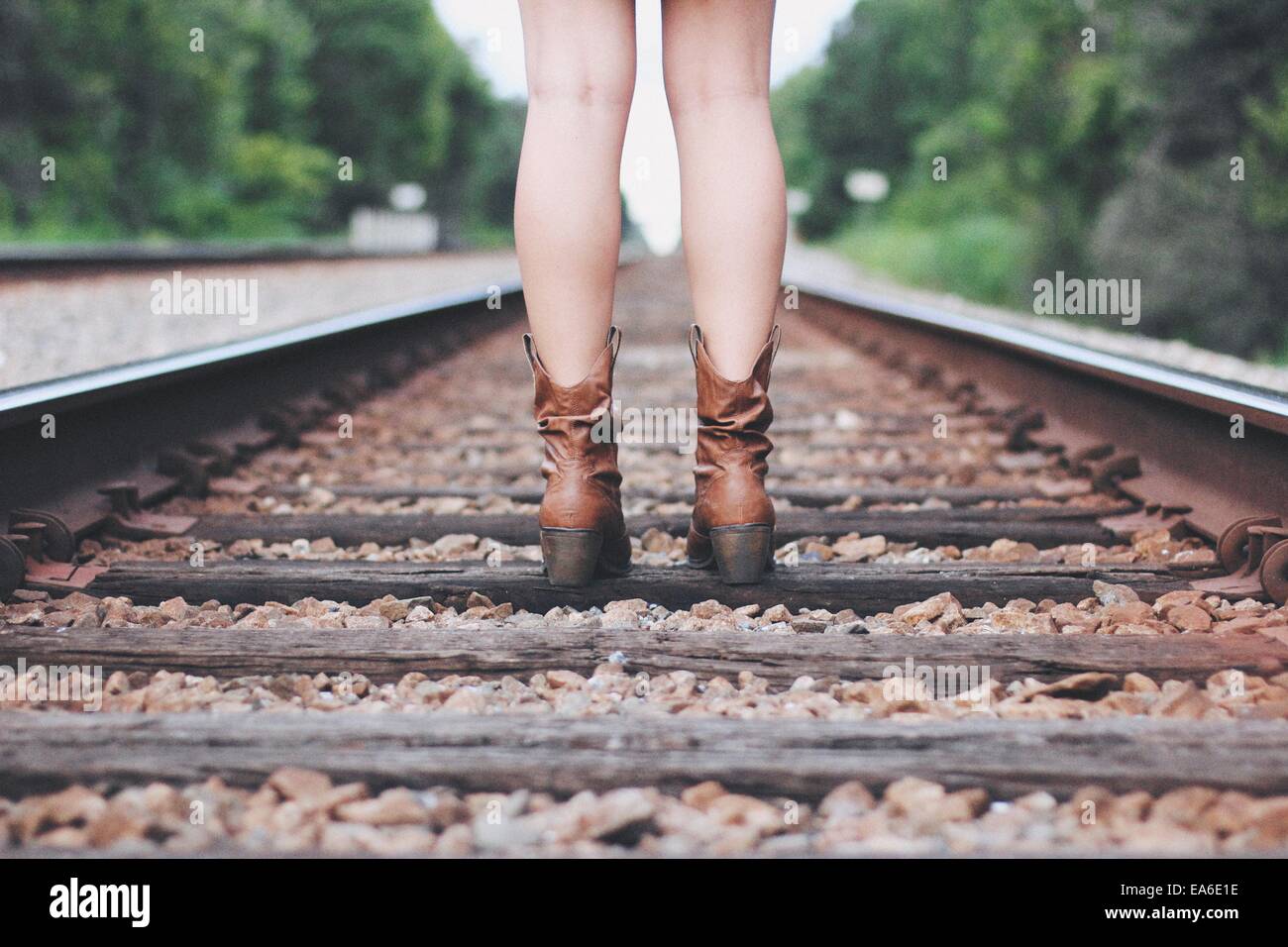 Ragazza adolescente in stivali in piedi sulle piste del treno Foto Stock