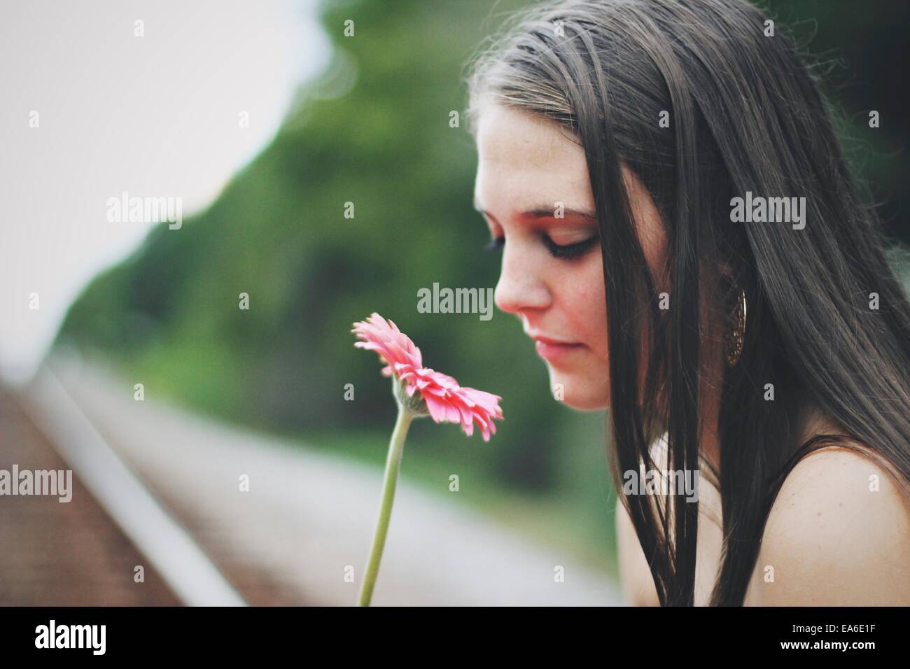 Giovane donna odore di gerbera fiore Foto Stock
