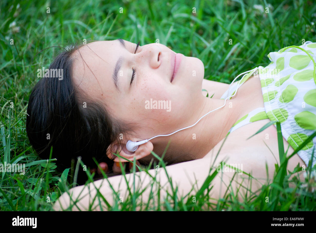 Ragazza distesa su erba ascolto di musica Foto Stock