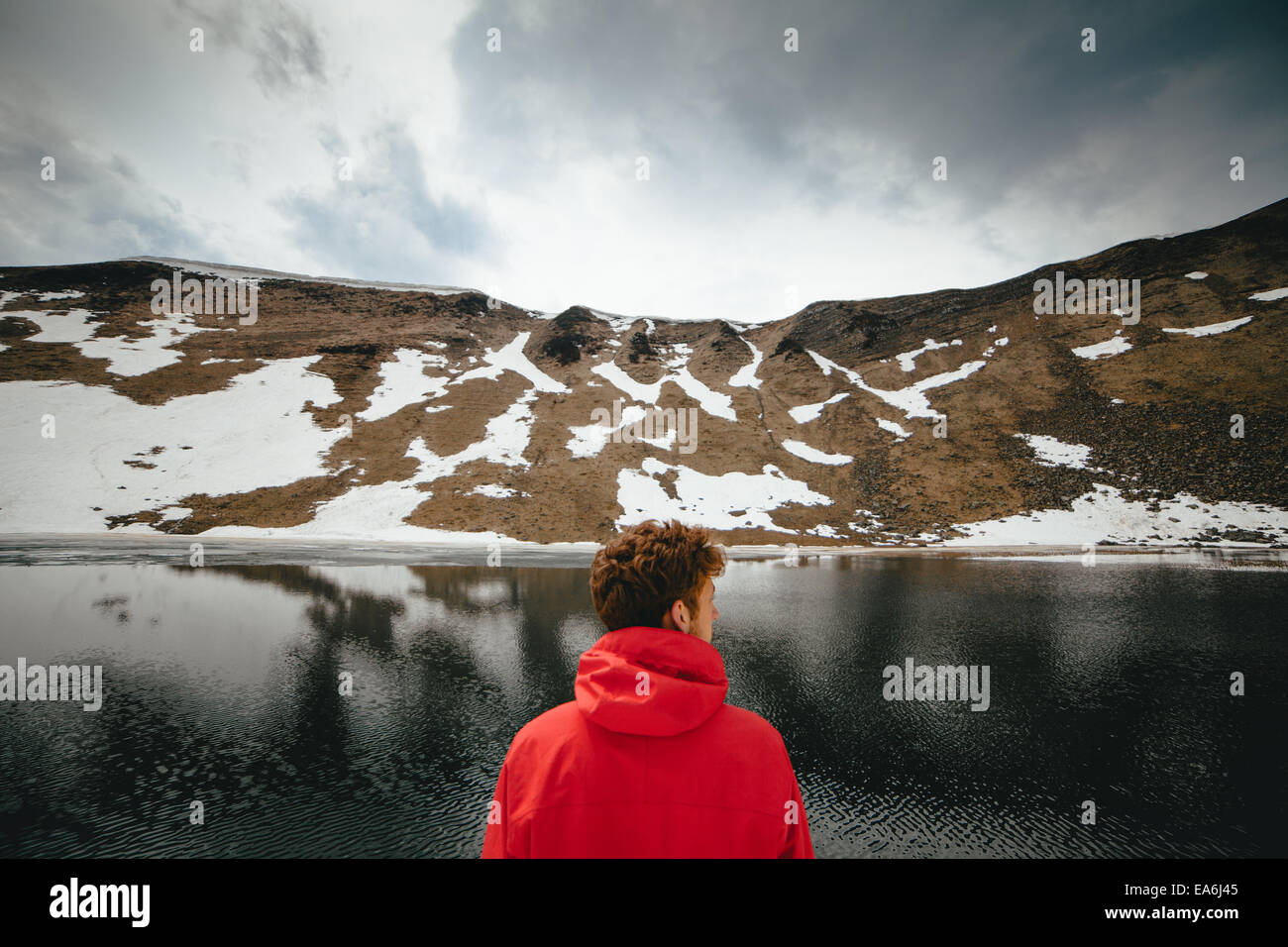 Vista posteriore del giovane uomo che guarda al lago di montagna Foto Stock