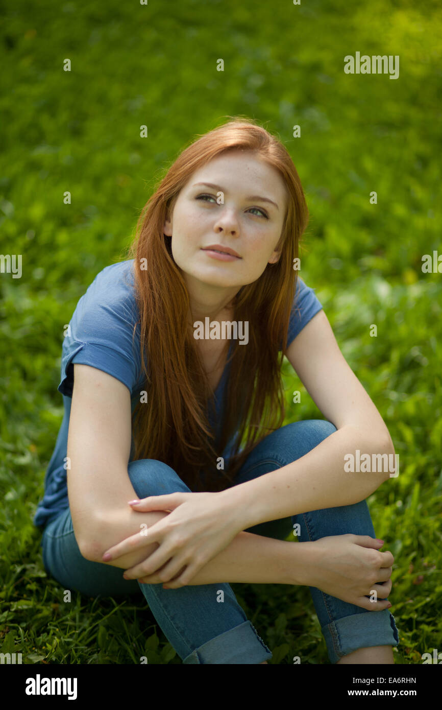 Bellissimi i Capelli rossi ragazza seduta sull'erba Foto Stock