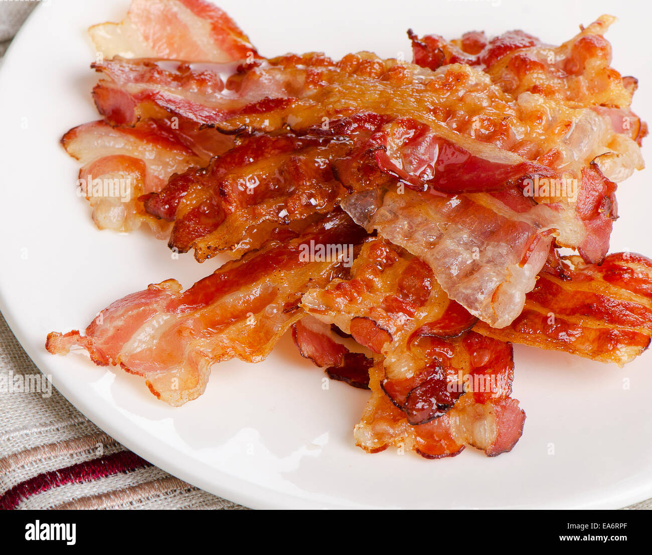 Bacon cotto rashers su una piastra bianca. Messa a fuoco selettiva Foto Stock