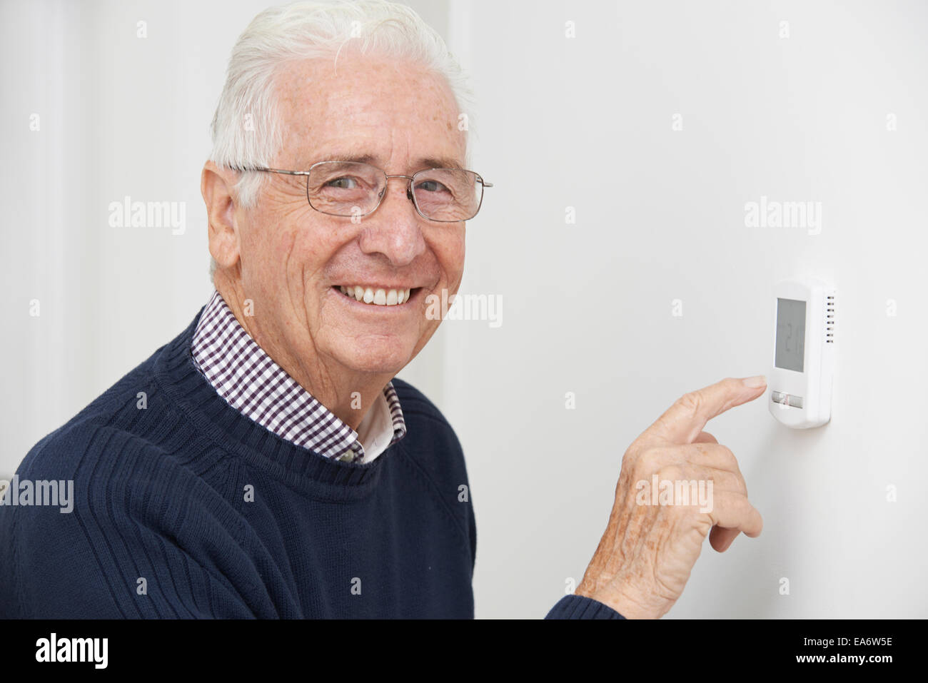 Senior sorridente uomo centrale di regolazione TERMOSTATO RISCALDAMENTO Foto Stock