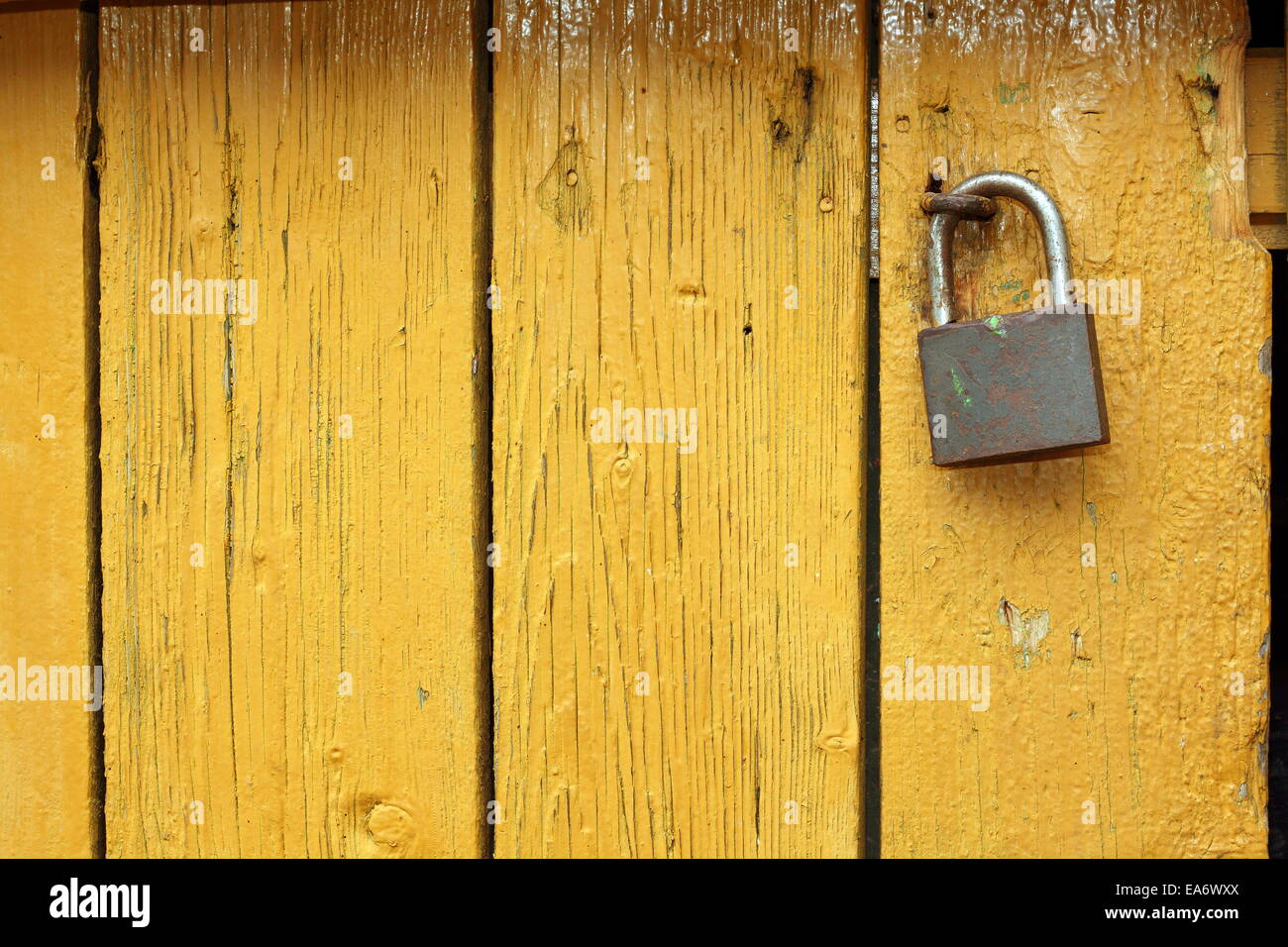 Vecchio lucchetto metallico su giallo porta di legno, interessante vista testurizzata Foto Stock