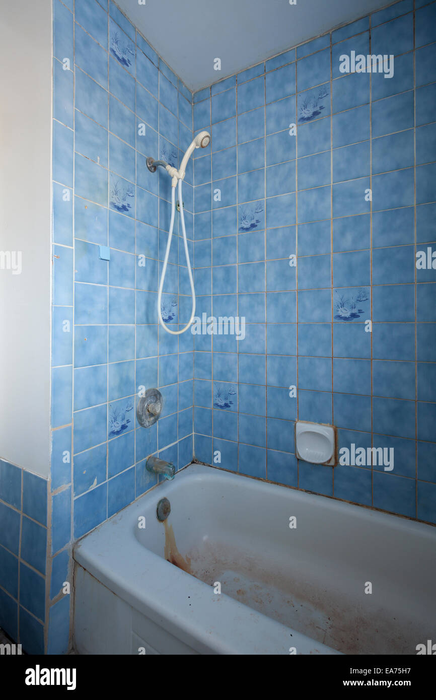 Un retrò e sudicio doccia e vasca da bagno con piastrelle blu in una casa abbandonata. Nei pressi di Oakville, Ontario, Canada. Foto Stock
